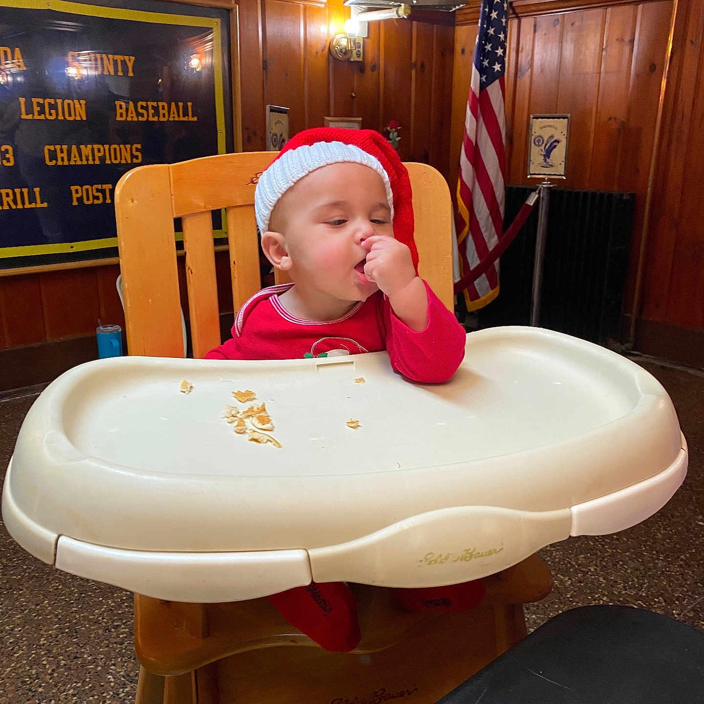 Mlijah joined the competition — help win amazing prizes! american_flag, baby, banner, baseball, child, cozy, crumbs, cute, eating, face, festive, high_chair, holiday, indoor, person, red_clothing, santa_hat, toddler, wood_paneling, wooden_chair