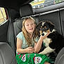 animal, backseat, black_and_white_dog, car_interior, casual_clothing, child, comfort, dog, friendship, green_pajamas, headrest, human, indoor, pet, portrait, puppy, santa_pattern, seatbelt, window, young_girl
