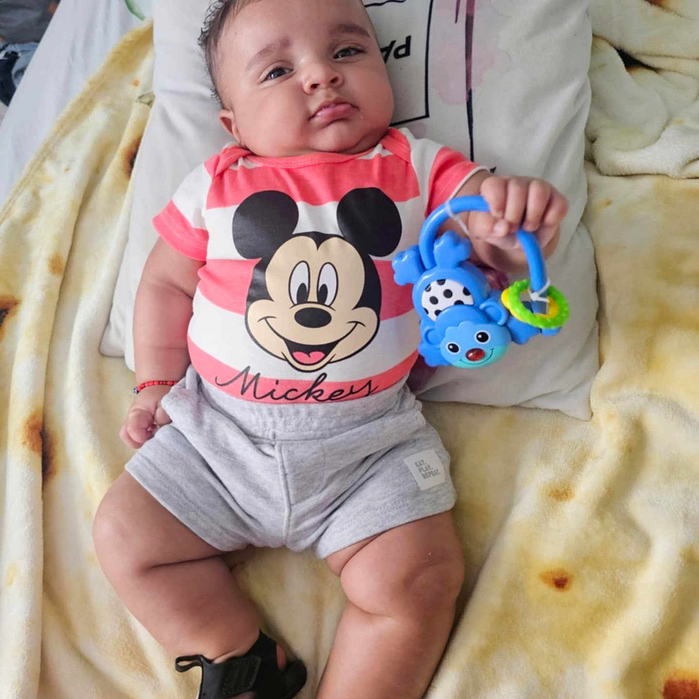 Yassiel Torres joined the competition — help win amazing prizes! baby, black_shoes, blanket, child, colorful, cute, face, footwear, hand, indoors, infant, legs, lying_down, mickey_mouse, pillow, shirt, shorts, smiling, soft_texture, toy