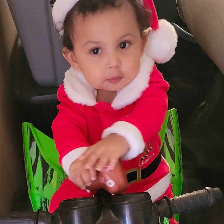 Prince'Aliajah is registered to the contest to win money with this photo: baby, bodypart, clothing, coat, cushion, face, finger, hand, hat, head, helmet, homedecor, hood, jacket, person, photography, portrait, sitting, transportation, vehicle