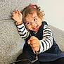 Azalia a rejoint le concours — aidez-le/la à gagner de superbes lots ! toddler, child, smile, curly_hair, glasses, striped_shirt, black_tights, blue_dress, couch, indoor, happy, playful, person, face, hand, sitting, cute, young_child, home, fun