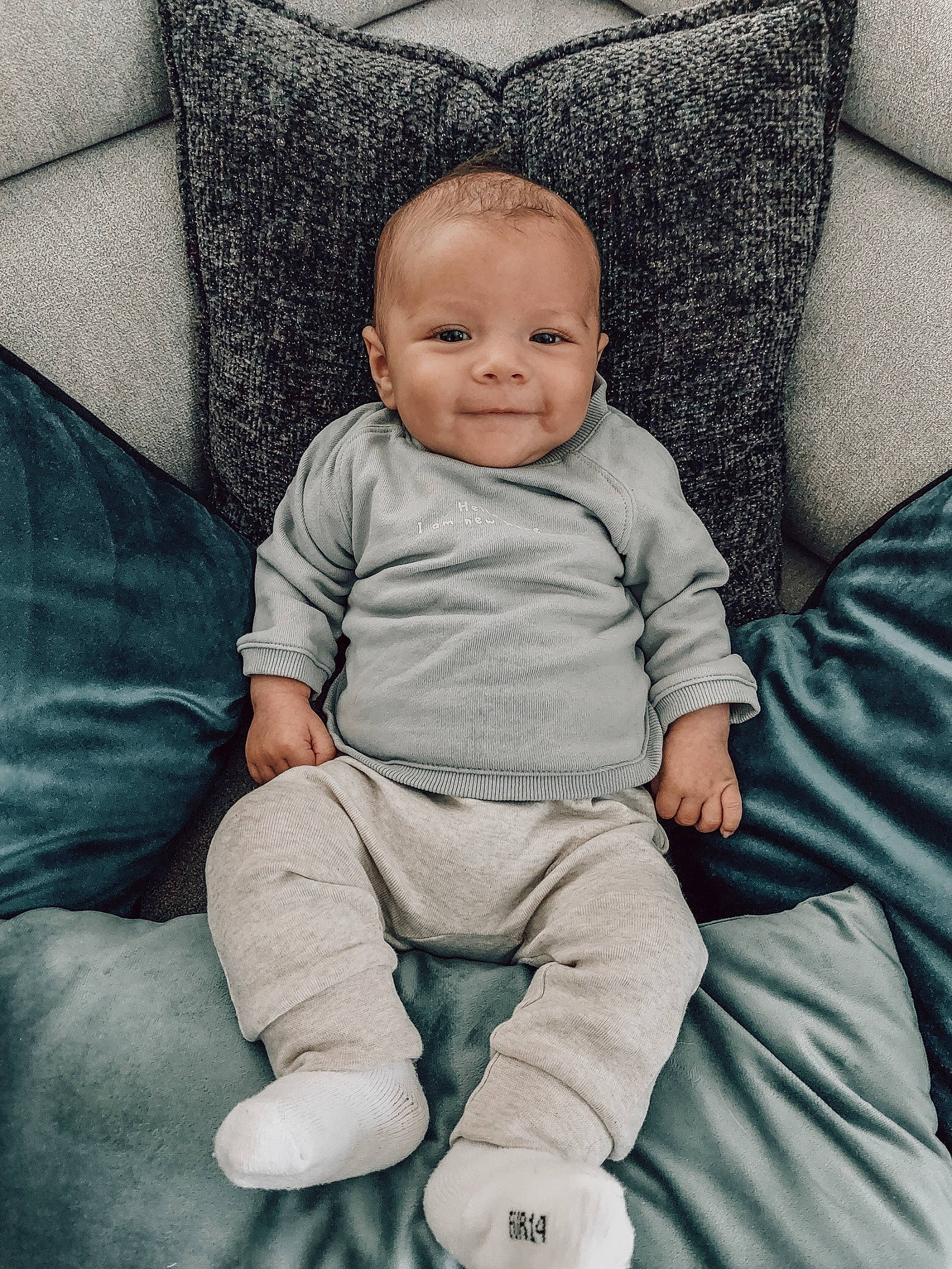 Lyo participe au concours pour gagner de l'argent avec cette photo : azure, baby, baby_toddler_clothing, cheek, comfort, couch, electric_blue, eye, face, flash_photography, happy, joy, linens, person, product, sitting, skin, sleeve, smile, t_shirt