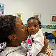 Ayla is registered to the contest to win money with this photo: baby, woman, kiss, affection, indoor, child, love, holding, sweater, person, portrait, cute, family, skin, face, expression, background, artwork, seated, clothing