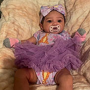 Elani is registered to the contest to win money with this photo: baby, pacifier, purple_tutu, headband, blanket, socks, infant, cute, soft_texture, indoor, child, clothing, lying_down, baby_girl, cozy, smiling_eyes, plush, comfortable, portrait, adorable