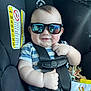 Azran is registered to the contest to win money with this photo: baby, child, car_seat, sunglasses, harness, toy, striped_clothing, reflection, infant, smile, chubby_cheeks, seatbelt, plastic_toy, blue_shirt, indoor, closeup, person, cute, sun_design, black_straps