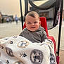 Azran is registered to the contest to win money with this photo: baby, blanket, lion_pattern, stroller, red, smile, face, child, outdoor, person, hoodie, cozy, happy, infant, portrait, cute, seated, expression, warm_light, blurred_background