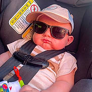 Azran is registered to the contest to win money with this photo: baby, child, car_seat, sunglasses, cap, harness, infant, cute, chubby_cheeks, comfortable, casual_clothing, seatbelt, relaxed, indoor, portrait, person, toddler, hat, sun_protection, resting