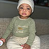Kairo joined the competition — help win amazing prizes! toddler, child, baby, sitting, hat, sweater, clothing, couch, indoor, person, face, expression, hand, long_sleeve, pants, footwear, holding, casual, portrait, young