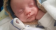 Kaven is registered to the contest to win money with this photo: baby, blanket, blue_hat, child, clothing, cozy, cute, face, hand, indoors, infant, knitted_hat, newborn, peaceful, portrait, resting, sleeping, soft, warm, white_blanket
