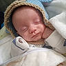 baby, blanket, blue_hat, child, clothing, cozy, cute, face, hand, indoors, infant, knitted_hat, newborn, peaceful, portrait, resting, sleeping, soft, warm, white_blanket
