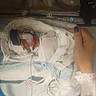 baby, bed, blanket, breathing_tube, care, clothing, hand, healthcare, hospital, incubator, infant, medical_equipment, monitoring_wires, nail_polish, newborn, person, premature_baby, swaddled, treatment, wristband