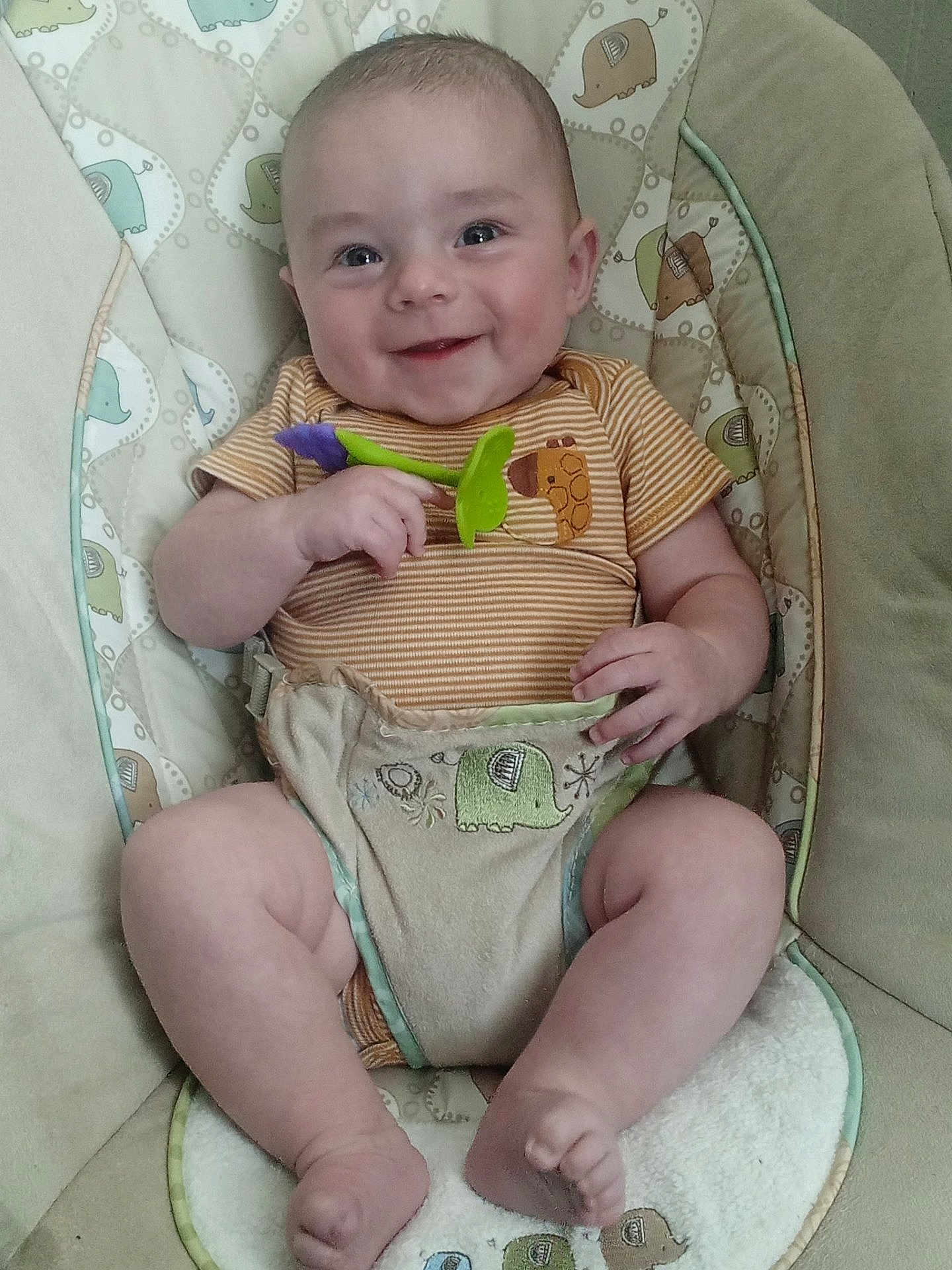 Royce is registered to the contest to win money with this photo: baby, smiling, infant, baby_seat, toy, cushion, elephant_pattern, clothing, striped_shirt, happy, cute, child, skin, legs, feet, hand, playful, indoors, comfort, portrait