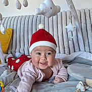 Emy a rejoint le concours — aidez-le/la à gagner de superbes lots ! baby, baby_toy, blanket, cardigan, child, couch, cute, face, giraffe_toy, happy, home, indoor, infant, play_area, plush, red_hat, smiling, soft_toys, star_mobile, toys