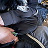 dog, sleeping, lap, person, hand, shoe, black_clothing, indoor, casual, resting, small_dog, white_and_black, footwear, sneaker, seated, comfort, clothing, relaxation, human, pet