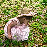 Brielle joined the competition — help win amazing prizes! child, toddler, girl, pink_dress, straw_hat, flowers, grass, leaves, outdoor, nature, curious, crouching, sunlight, greenery, plants, spring, exploration, young_child, garden, daylight