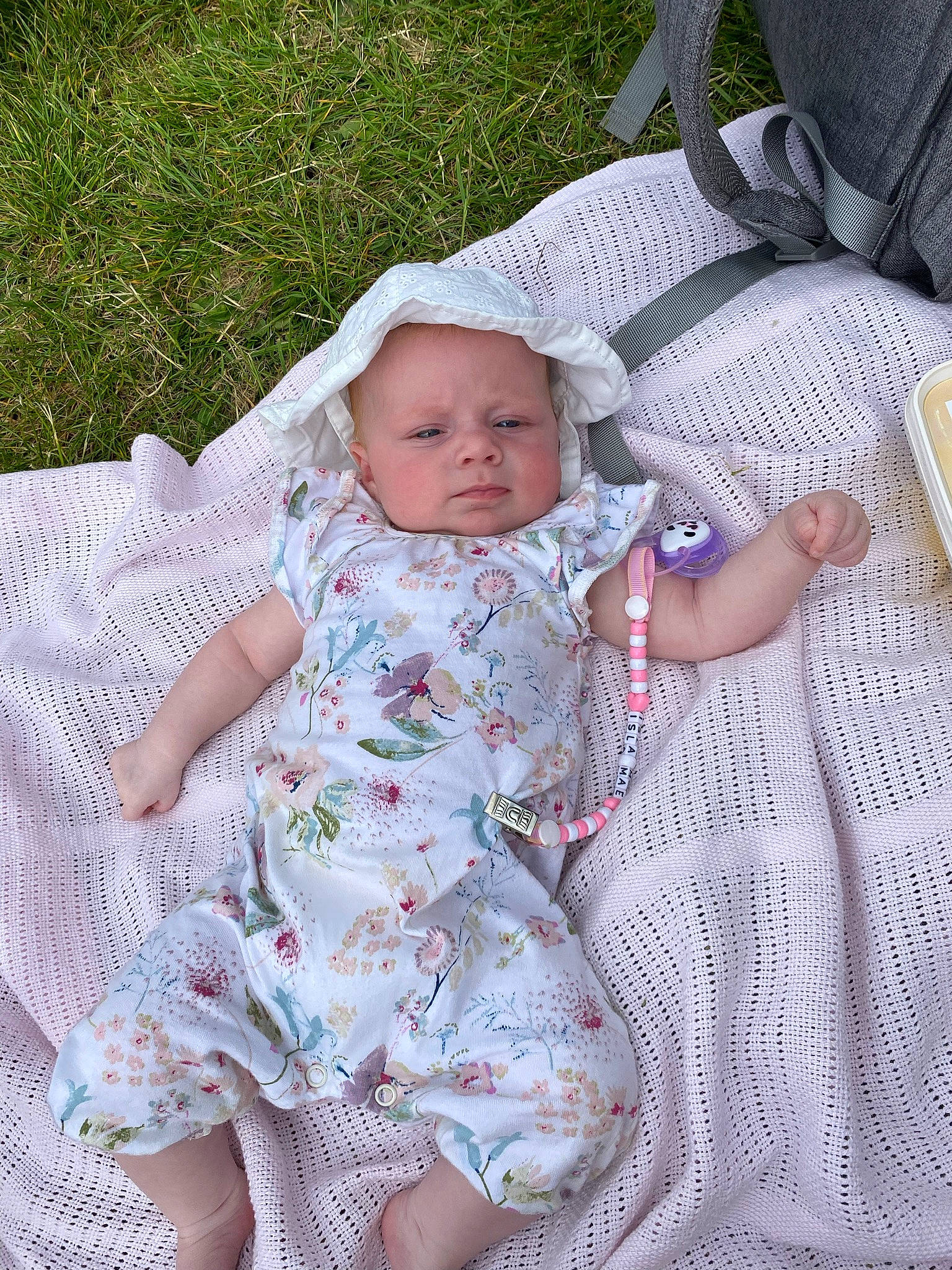 Isla-mae is registered to the contest to win money with this photo: arm, baby, baby_products, baby_toddler_clothing, cheek, child, comfort, dress, finger, grass, hand, headwear, human_body, lap, linens, pattern, person, plate, sitting, skin