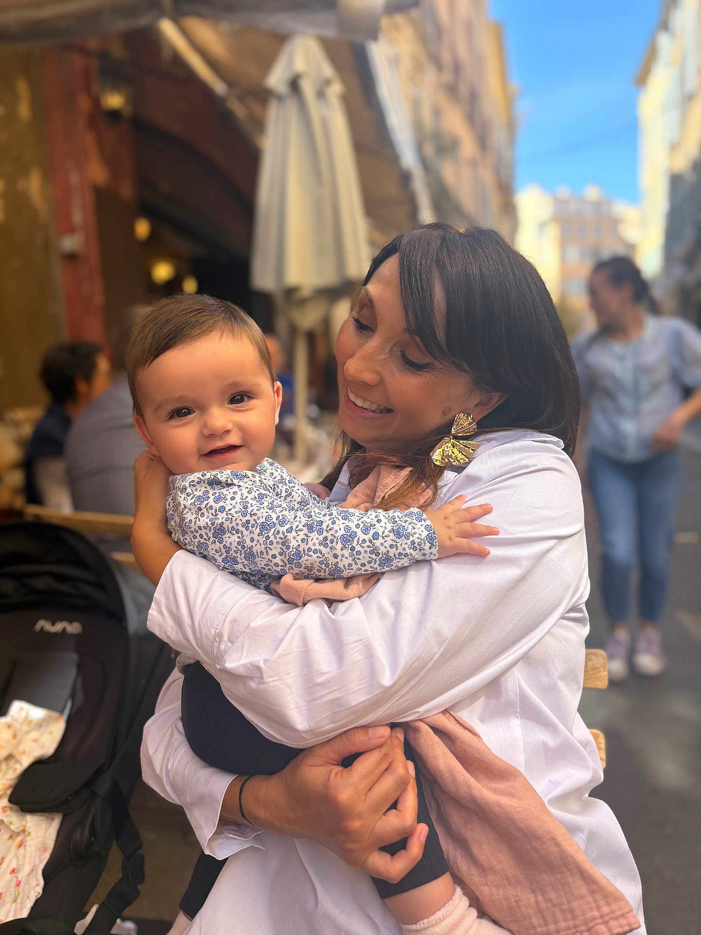 Ghjulia-Victoria a rejoint le concours — aidez-le/la à gagner de superbes lots ! baby, woman, child, smile, hug, outdoor, cafe, people, street, daylight, clothing, stroller, happy, portrait, person, holding, casual, urban, family, love