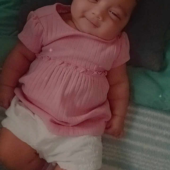 D'Zakaryi joined the competition — help win amazing prizes! baby, blanket, casual, child, childhood, cozy, cute, happy, heart_emoji, indoors, infant, lying_down, pillow, pink_clothing, portrait, resting, smiling, soft_lighting, toddler, white_shorts