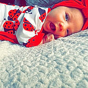 Morgan joined the competition — help win amazing prizes! baby, infant, child, smiling, red_headband, ladybug_outfit, blanket, soft_texture, lying_down, cute, happy, face, portrait, closeup, indoors, cozy, bright_colors, skin, hand, expression