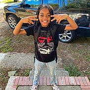 Noah joined the competition — help win amazing prizes! child, smiling, posing, braided_hair, black_tshirt, jeans, sneakers, backpack, front_porch, concrete, brick, car, suv, suburban, street, mailbox, trash_bins, daylight, outdoor, happy