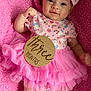baby, infant, girl, pink, tutu, headband, floral, blanket, soft, cute, milestone, wooden_sign, smiling, lying_down, clothing, portrait, child, happy, skin, small