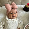 baby, infant, pink_bow, headband, white_clothing, smile, face, cute, indoor, blanket, soft_texture, dessert, chocolate, cake, food, portrait, child, cozy, happy, resting
