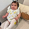 Reina Antonella is registered to the contest to win money with this photo: baby, child, infant, sitting, couch, sofa, pillows, portrait, smiling, happy, face, eyes, hair_bows, dress, lemon_pattern, white_socks, indoors, home, cozy, photography