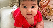 Reina Antonella is registered to the contest to win money with this photo: baby, child, infant, portrait, smiling, wide_eyes, red_outfit, hair_bow, cherry_bow, sitting, crawling, sofa, couch, cushions, indoor, home, close_up, adorable, bracelet, photography