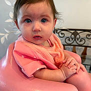 Charlotte joined the competition — help win amazing prizes! baby, child, pink, seat, clothing, hands, face, portrait, indoor, person, expression, curly_hair, looking_at_camera, cute, sitting, young_child, infant, skin, human, closeup