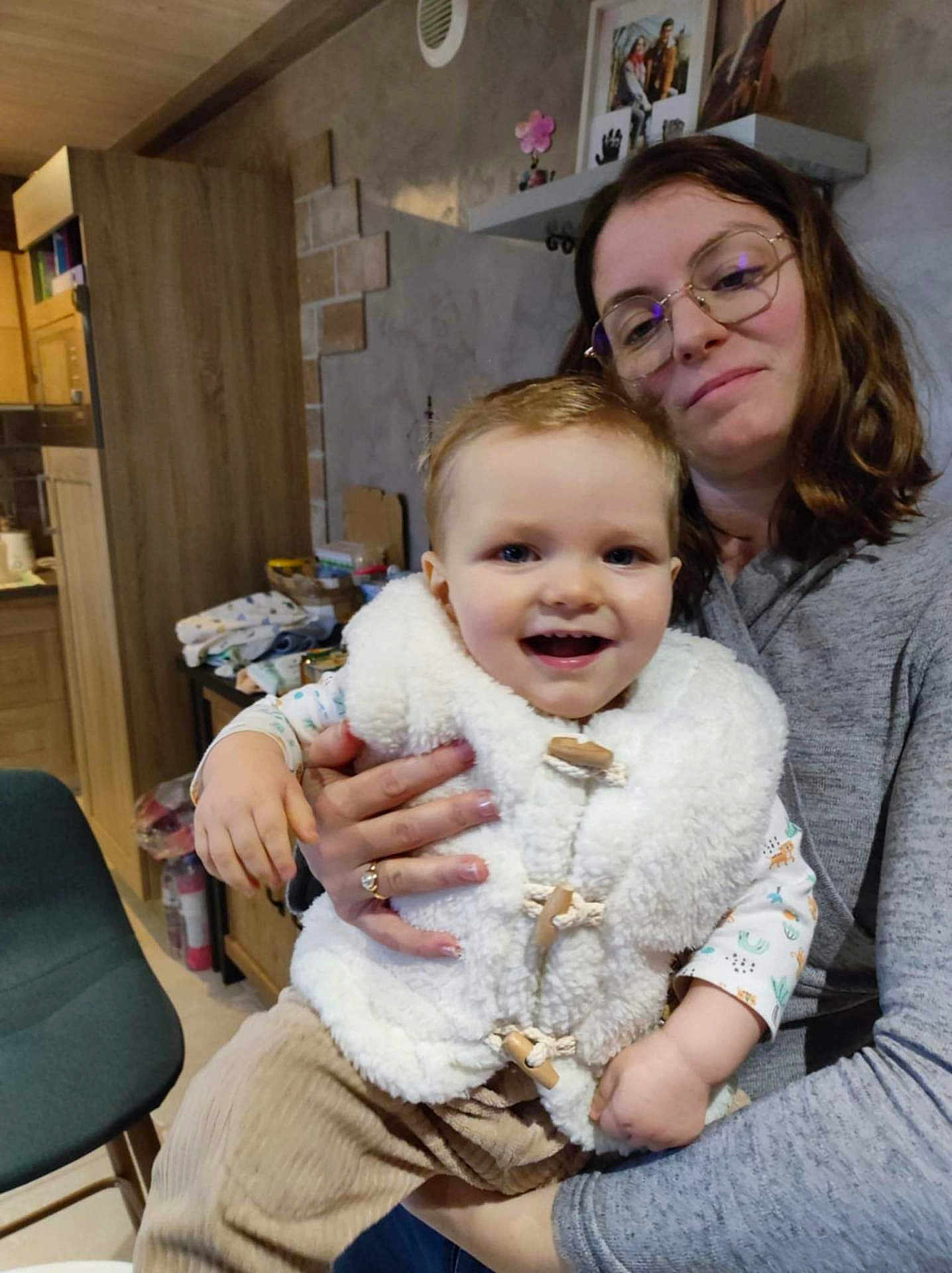 Oscar a rejoint le concours — aidez-le/la à gagner de superbes lots ! toddler, child, woman, glasses, smile, indoor, kitchen, vest, corduroy_pants, holding, family, happy, person, portrait, clothing, casual, home, warm_lighting, furniture, background