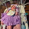 newborn, baby, hospital_bassinet, pacifier, purple_dress, mittens, headband, plush_toy, blanket, socks, infant, sleeping, clothing, baby_care, medical_equipment, wooden_floor, person, cute, indoor, portrait