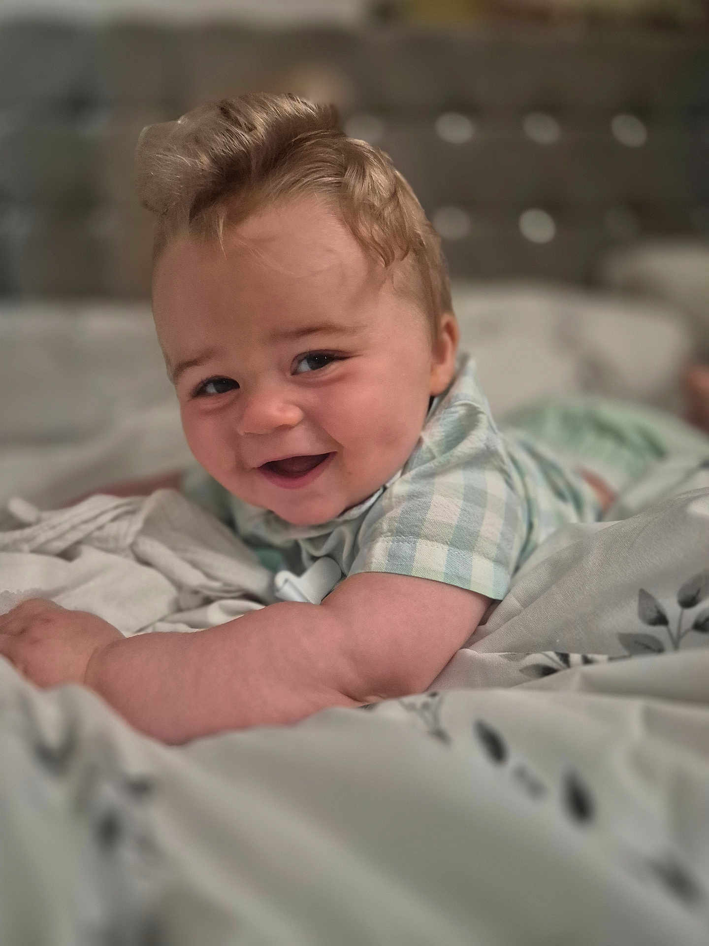 Louie is registered to the contest to win money with this photo: baby, smiling, child, bed, blanket, clothing, cute, face, happy, infant, indoors, laying, person, portrait, soft, toddler, young, cute_expression, cozy, relaxed