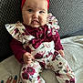 baby, child, headband, red, floral_outfit, couch, smile, hand, nails, blue_eyes, cute, clothing, footwear, sitting, indoor, person, infant, portrait, fingers, fabric