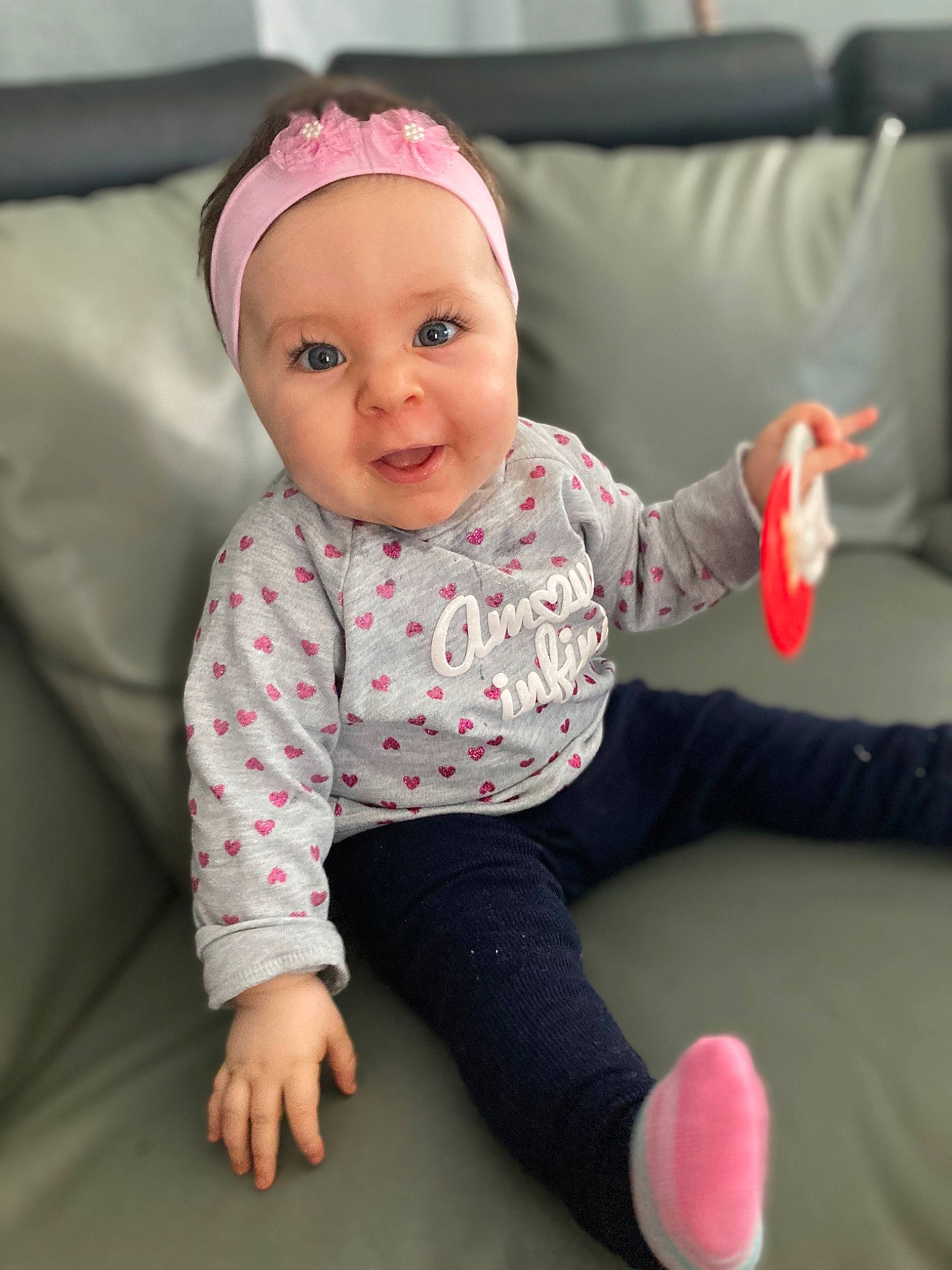 Britney a rejoint le concours — aidez-le/la à gagner de superbes lots ! baby, baby_laughing, baby_playing_with_toys, baby_products, baby_toddler_clothing, bonnet, child, comfort, costume_accessory, couch, hair_accessory, hand, headband, headpiece, headwear, living_room, person, pink, sitting, sock