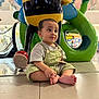 toddler, child, barefoot, overalls, striped_shirt, sitting, indoor, statue, bee_statue, colorful, green, yellow, red, floor, tiles, mall, playful, curious, young_child, sculpture
