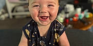Wesley is registered to the contest to win money with this photo: arm, baby, background, bookshelf, child, clothing, cute, expression, face, furniture, happy, indoors, person, room, sitting, skin, smiling, tattoo, television, toy