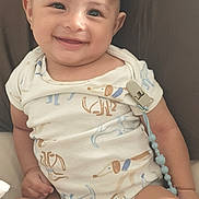 Nicholas is registered to the contest to win money with this photo: baby, casual, child, clothing, cute, cute_expression, face, fingers, hand, happy, indoors, infant, onesie, pacifier_clip, portrait, relaxed, sitting, skin, smiling, young