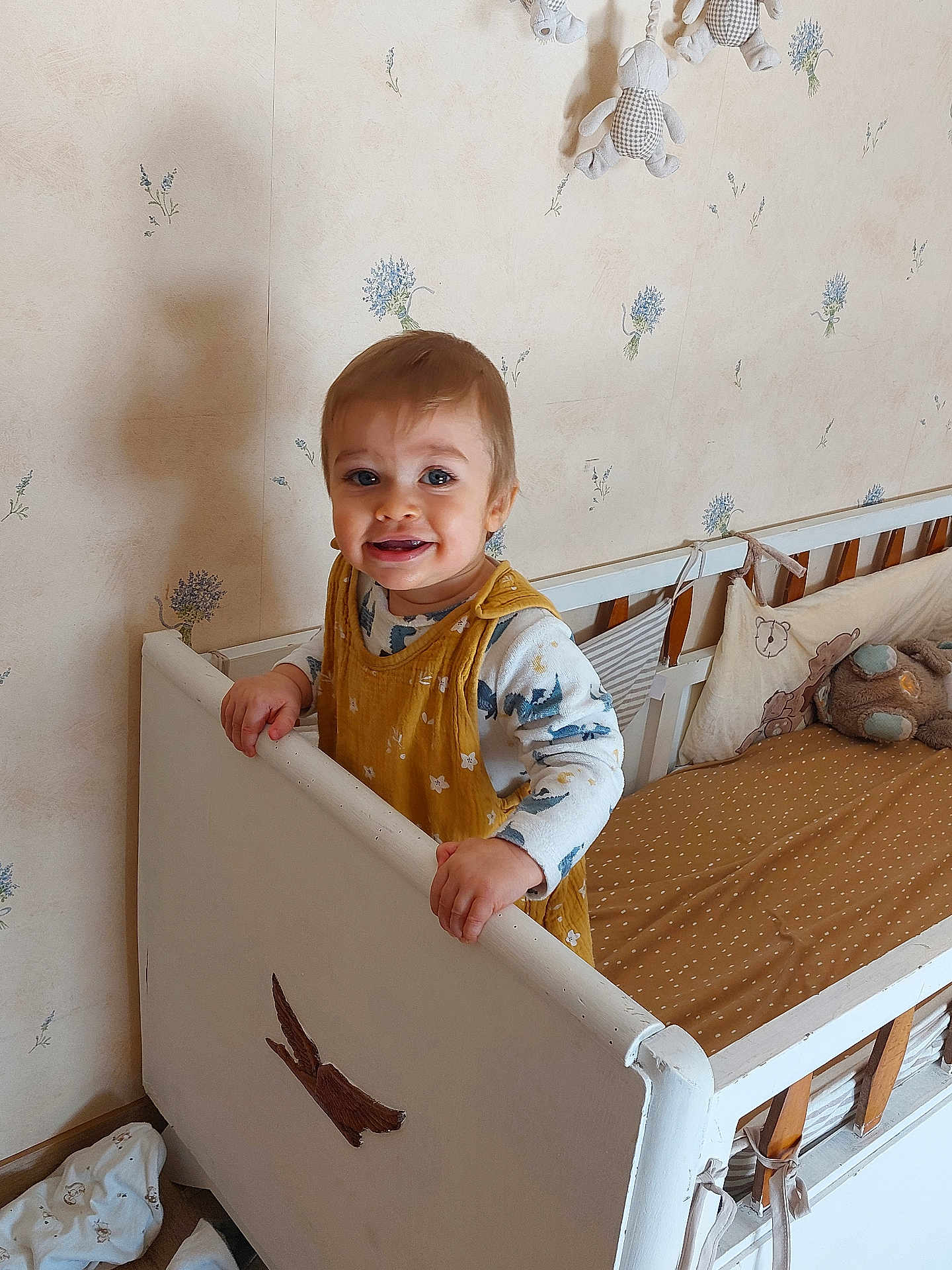 Arthur a rejoint le concours — aidez-le/la à gagner de superbes lots ! toddler, crib, child, smiling, indoor, toy, wallpaper, bedroom, yellow_clothing, wood, baby, furniture, happy, face, person, plush_toy, decor, pattern, hand, standing