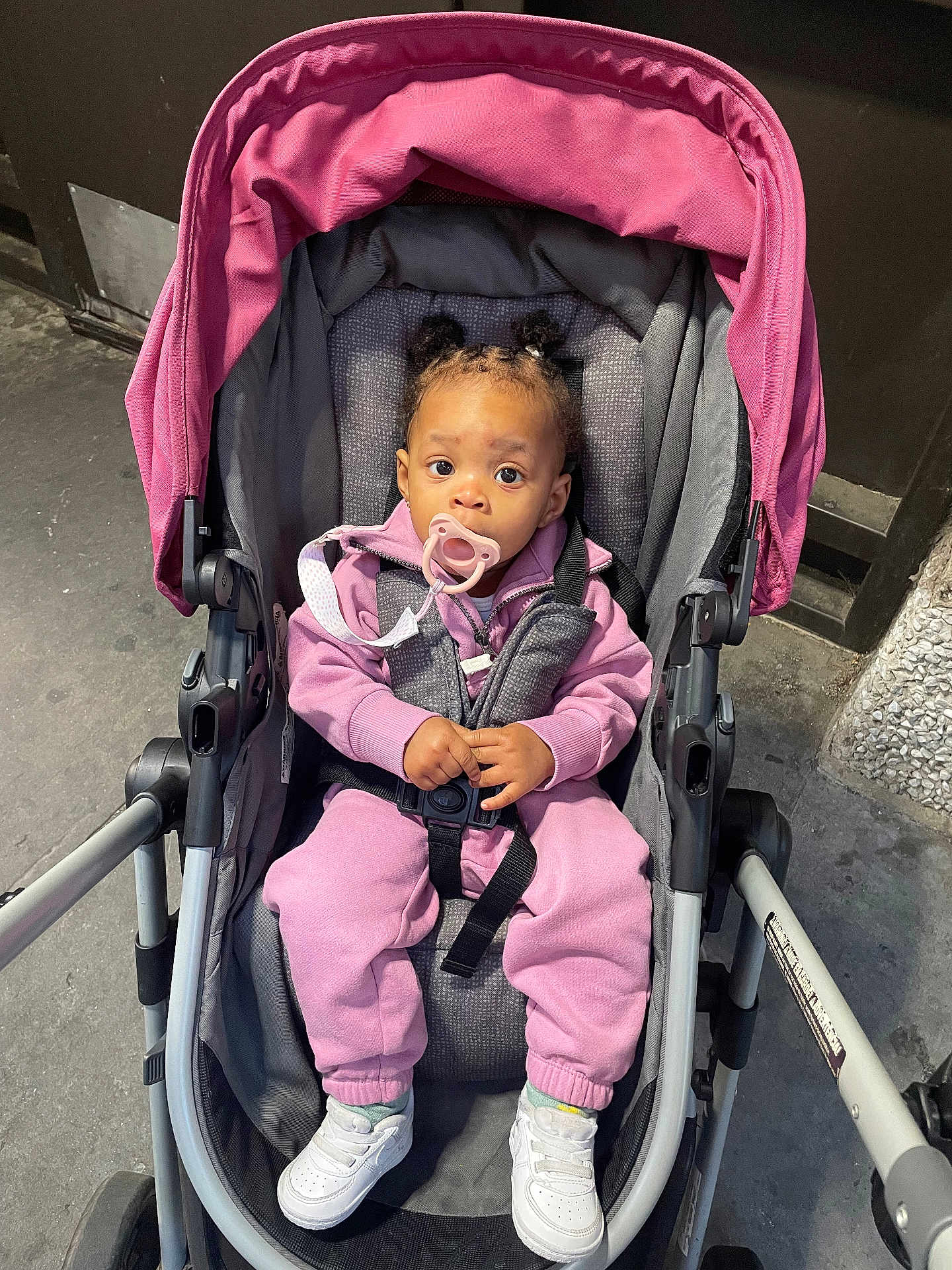 Kahmiya joined the competition — help win amazing prizes! baby, stroller, pacifier, pink_clothing, sneakers, child, urban, sidewalk, cute, infant, hair_buns, jacket, pants, sitting, outdoor, person, footwear, seat_belt, expression, young_child