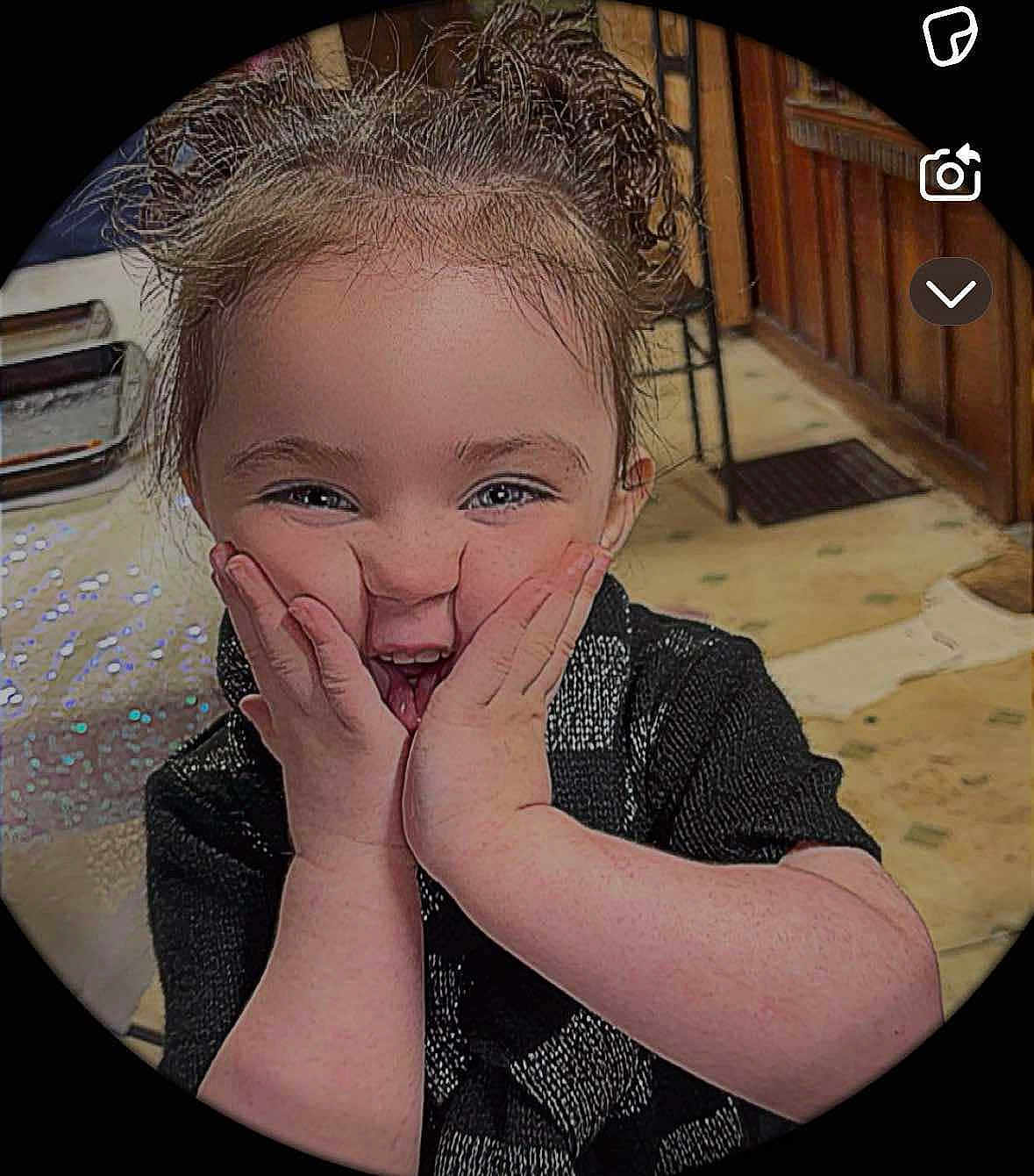 Kelly is registered to the contest to win money with this photo: child, happy, smiling, face, hands, indoor, curly_hair, person, expression, joy, black_clothing, floor, wooden_furniture, background, portrait, cute, young, closeup, vignette, playful