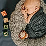 newborn, baby, sleeping, blanket, plush_toy, lion, alphabet_blocks, letters, soft_texture, cushion, wrapped, infant, child, resting, cozy, indoor, cute, portrait, peaceful, nursery