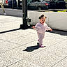 toddler, child, sidewalk, urban, sunlight, shadow, pole, car, parking, person, jogging_suit, pink_shoes, happiness, outdoor, daytime, concrete, street, walking, city, casual_clothing