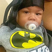 Kavalli-Roman joined the competition — help win amazing prizes! baby, pacifier, batman_logo, headwrap, child, person, adult, closeup, gray_shirt, black_headwrap, infant, holding, portrait, indoor, calm, cute, young_child, face, sitting, clothing