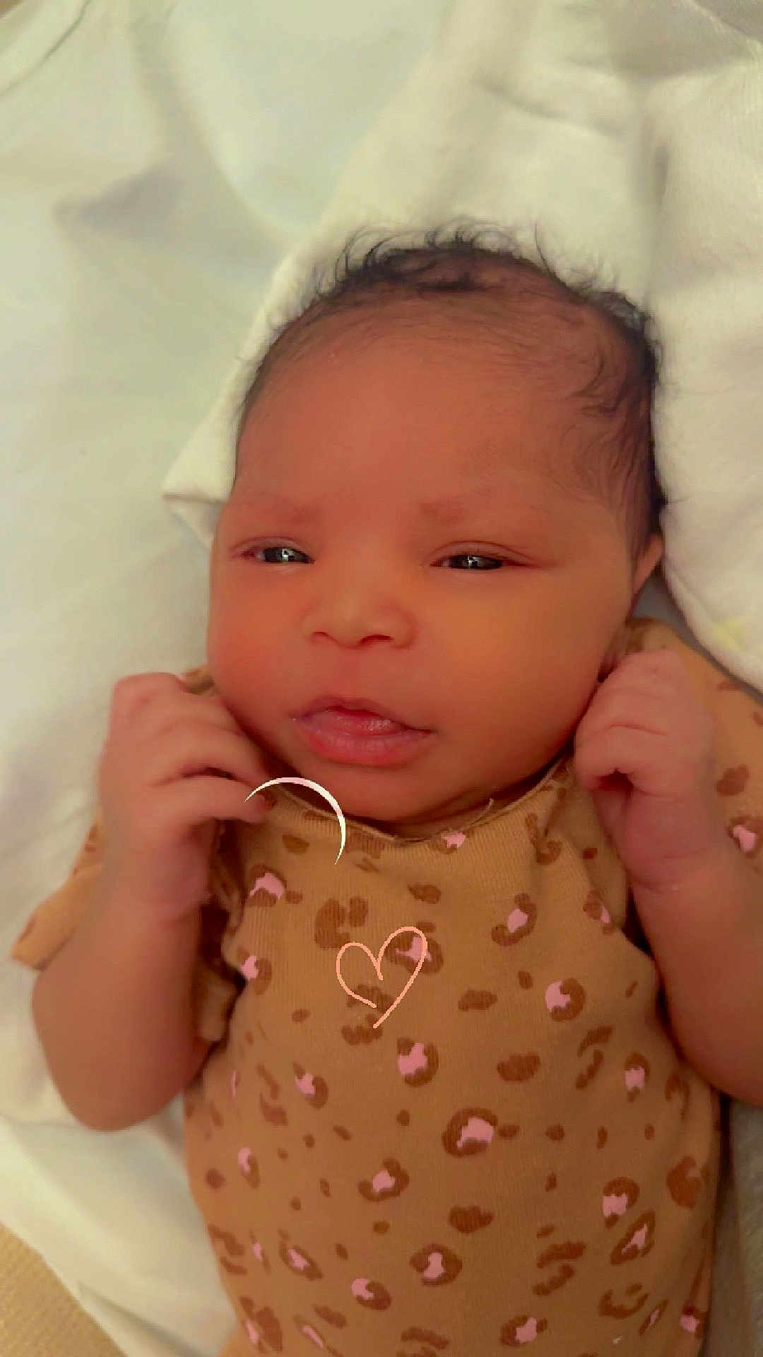 Aurelia is registered to the contest to win money with this photo: baby, newborn, infant, face, hands, blanket, clothing, leopard_print, onesie, lying_down, cute, soft, skin, head, expression, indoors, portrait, child, sleepwear, cozy