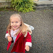 Joy a rejoint le concours — aidez-le/la à gagner de superbes lots ! child, girl, smiling, outdoor, coat, hoodie, backpack, gravel, blue_eyes, long_hair, building, bush, steps, door, casual_clothing, footwear, portrait, happy, person, daylight