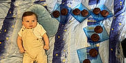 Malône a rejoint le concours — aidez-le/la à gagner de superbes lots ! baby, child, bedspread, pillow, muffins, plate, blue, yellow, beige_clothing, socks, indoor, lying_down, food, dessert, pattern, cute, resting, cozy, snack, portrait