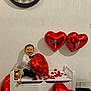 Malône participe au concours pour gagner de l'argent avec cette photo : baby, child, balloon, heart, red, bench, rose_petals, clock, wall, floor, toy, smile, indoors, celebration, party, white_shirt, black_bow_tie, furniture, happy, cute