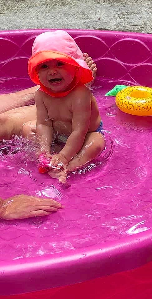 Averi is registered to the contest to win money with this photo: baby, baby_products, barechested, bathing, cap, chest, child, fun, happy, headwear, leisure, magenta, party_supply, person, pink, play, purple, recreation, smile, swimming_pool