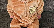 Xavier is registered to the contest to win money with this photo: baby, bear_costume, child, clothing, couch, curious, cute, ears, fabric, face, home, hood, indoor, infant, onesie, plush, portrait, sitting, soft_texture, wide_eyes