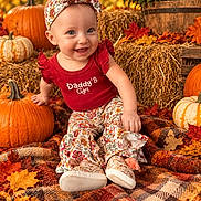 Anna joined the competition — help win amazing prizes! baby, child, smiling, portrait, autumn, fall, pumpkins, hay_bale, flowers, leaves, outdoor, seasonal, headband, bow, red_outfit, patterned_clothing, sitting, blanket, rustic, happy